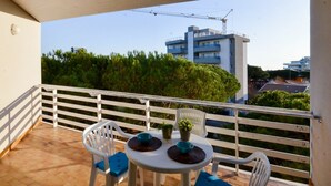 Een balkon met een tafel en stoelen, met uitzicht op een bouwkraan en gebouwen op de achtergrond.