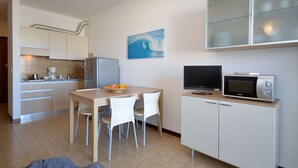 Een compacte keuken met een eethoek, een magnetron en een schilderij aan de muur.