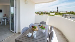 Ein Balkon mit Tisch für zwei Personen, einem Blumentopf und Blick auf die Stadtlandschaft.
