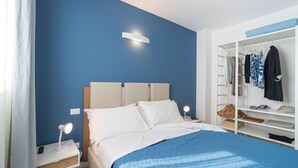 Ein Schlafzimmer mit Bett, Nachttischen, einem Kleiderschrank und einem Beistelltisch.