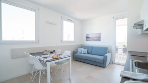 Ein heller, moderner Wohnbereich mit Essbereich, einer Couch und einer Küchenzeile.