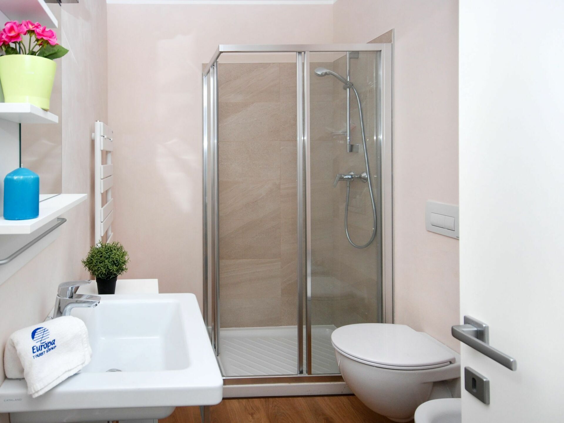 A modern bathroom with a glass-enclosed shower, a white sink, and a toilet.