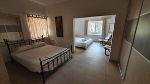 Un dormitorio con una cama individual, una mesita, una silla y una ventana con cortinas.