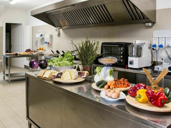 Una cocina industrial con electrodomésticos de acero inoxidable, diversos alimentos a la vista y una distribución limpia y ordenada.