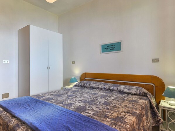 Un dormitorio con cama, armario, mesita de noche y un cartel en la pared.