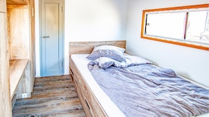 A small, single-bed room with a wooden floor, a door, and a window with a wooden frame. - Awesome ship in Hennigsdorf with lake view (Hennigsdorf)