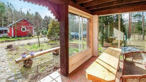 A wooden cabin with a large glass door and windows, a bench, and a chair outside. - 3 bedroom amazing home in Legbad (Legbad)