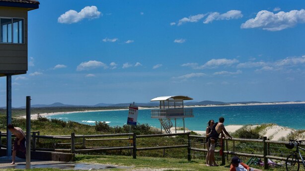 A coastal view with a wooden fence, a lifeguard tower, and a beach area.
