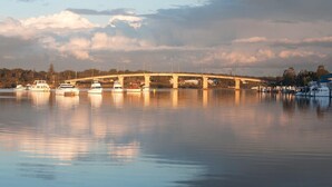 A bridge over calm water with boats docked nearby.