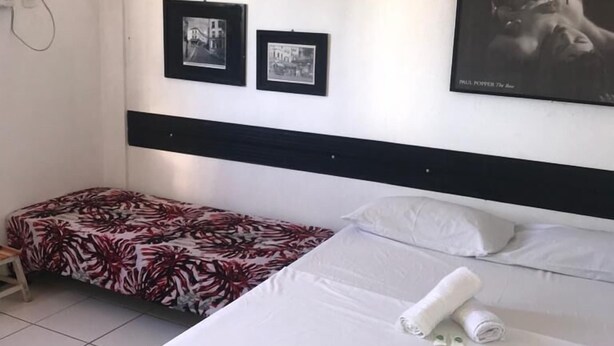 Une chambre d’hôtel avec un lit, une chaise et deux tableaux encadrés au mur.