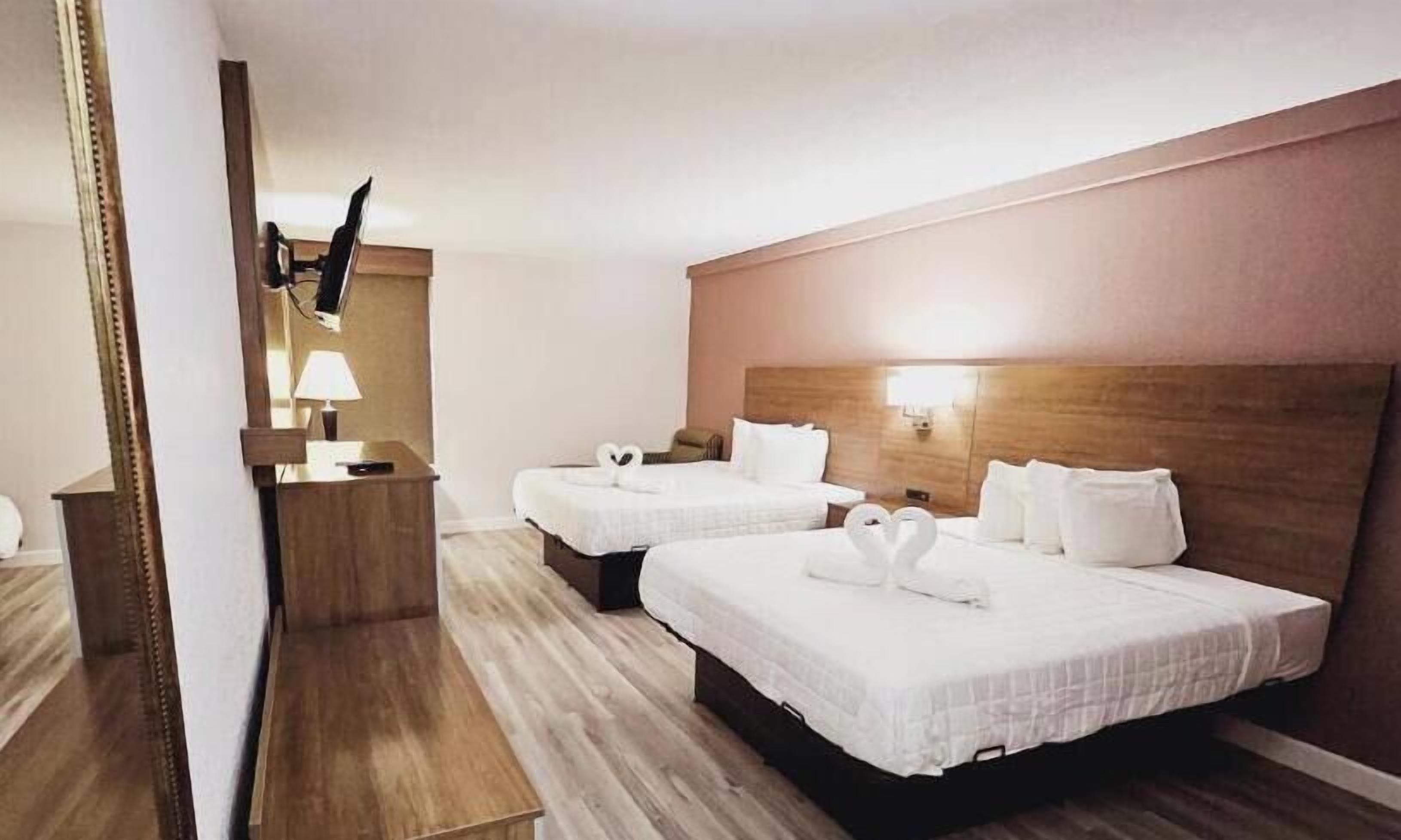 Habitació d'hotel amb dos llits, escriptori, mirall i televisió.