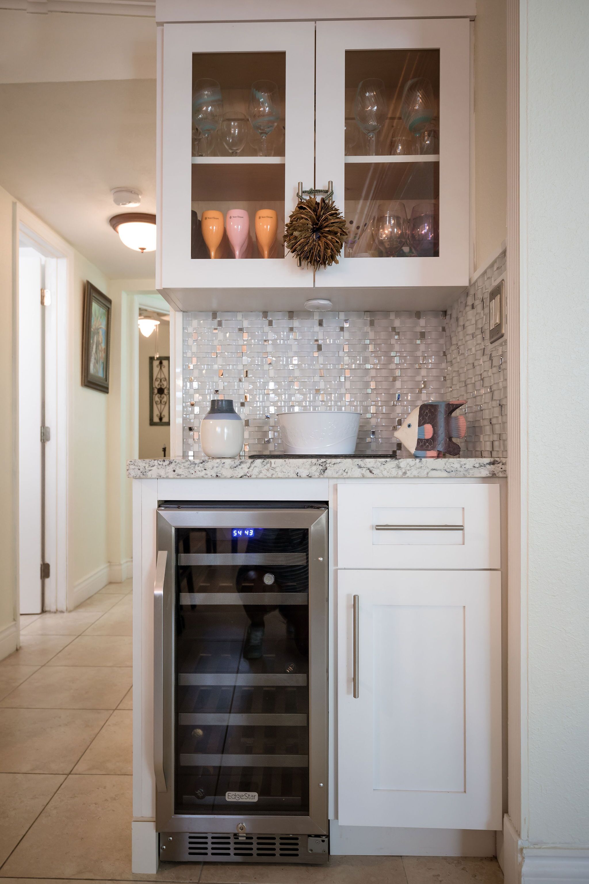 Una cocina con horno empotrado, microondas y estante para vinos.