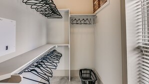 A compact, modern closet with multiple hanging spaces and a built-in laundry basket.