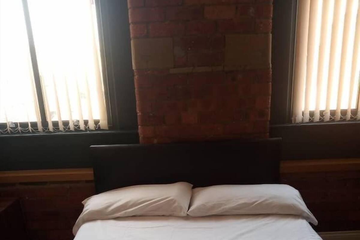 A neatly made bed with white linens and a folded white towel in the center.