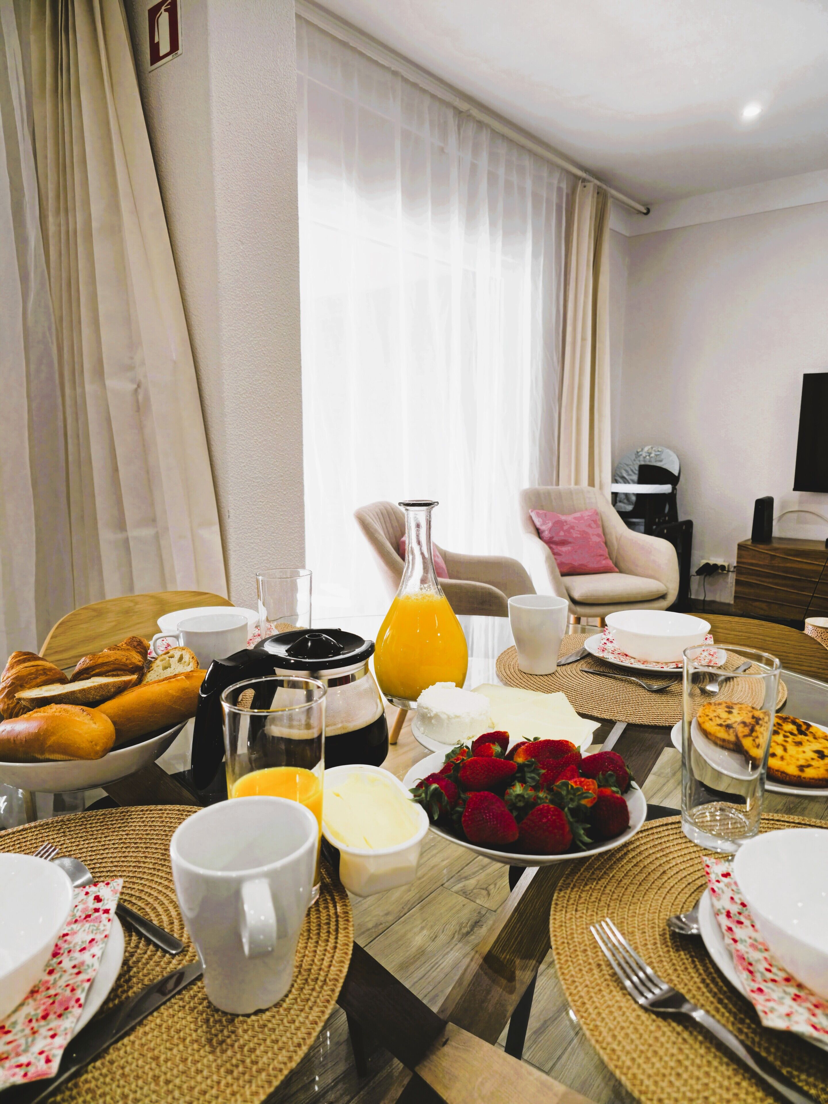 A breakfast setting with croissants, strawberries, and a coffee pot.