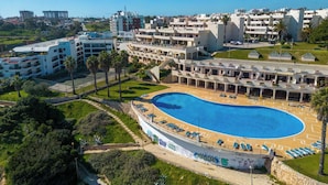 Een resort met een groot zwembad, meerdere gebouwen en een helder uitzicht op de omgeving.