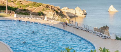 A swimming pool with a view of the sea and rocky cliffs.