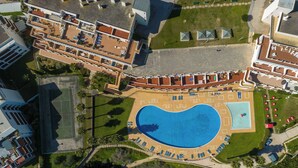 Luchtbeeld van een resort met een groot zwembad, meerdere gebouwen en een strandgebied.