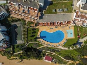 Vista aérea de um resort com uma grande piscina, vários edifícios e uma área de praia.