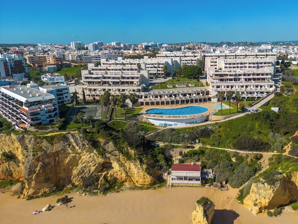Um hotel à beira-mar com vários edifícios, uma piscina e uma área de praia.