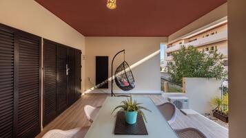 A modern outdoor seating area with a table, chairs, a hanging chair, and a potted plant.