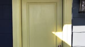 Uma porta fechada com maçaneta e fechadura, em um prédio com paredes pintadas em cores claras e escuras contrastantes.