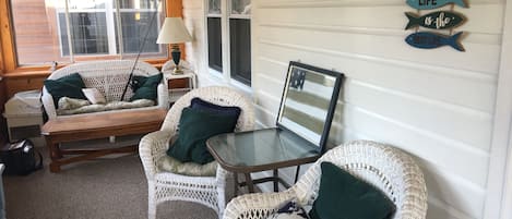 A cozy room with wicker furniture, a small table, and a wall-mounted sign.