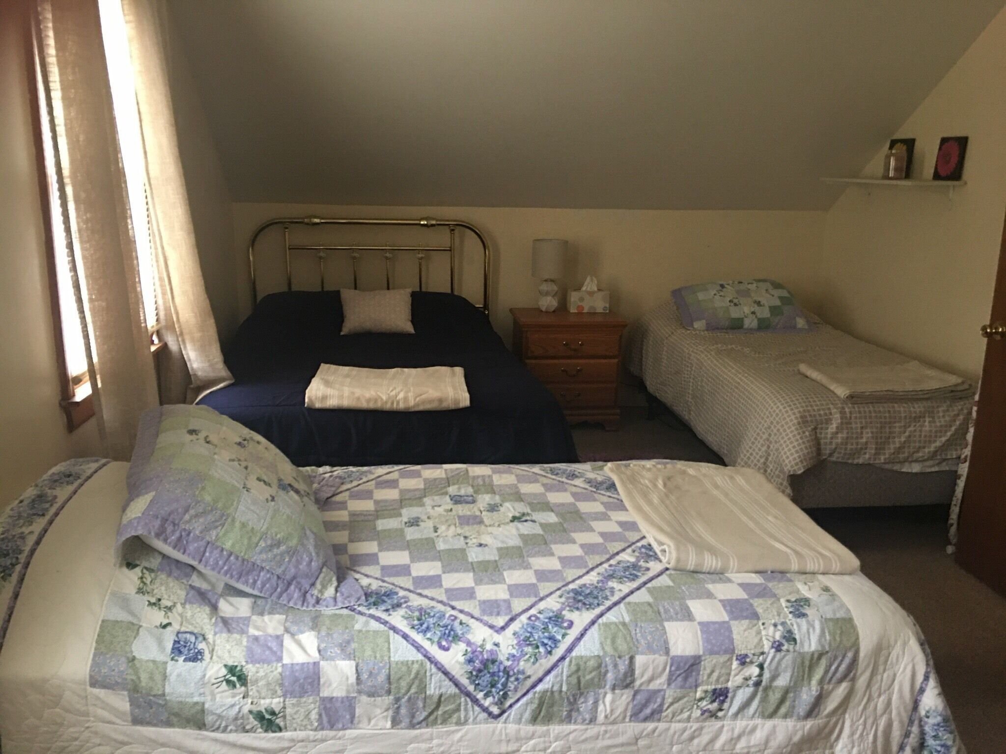 A bedroom with two beds, a nightstand, and a dresser.
