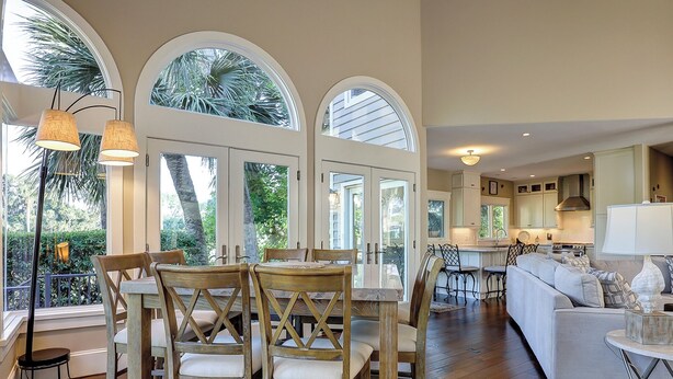 A spacious kitchen with a central island, a dining area with wooden chairs, and a living area with a sofa.