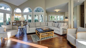 A spacious living room with a large sectional sofa, a coffee table, and a dining area with a table and chairs.