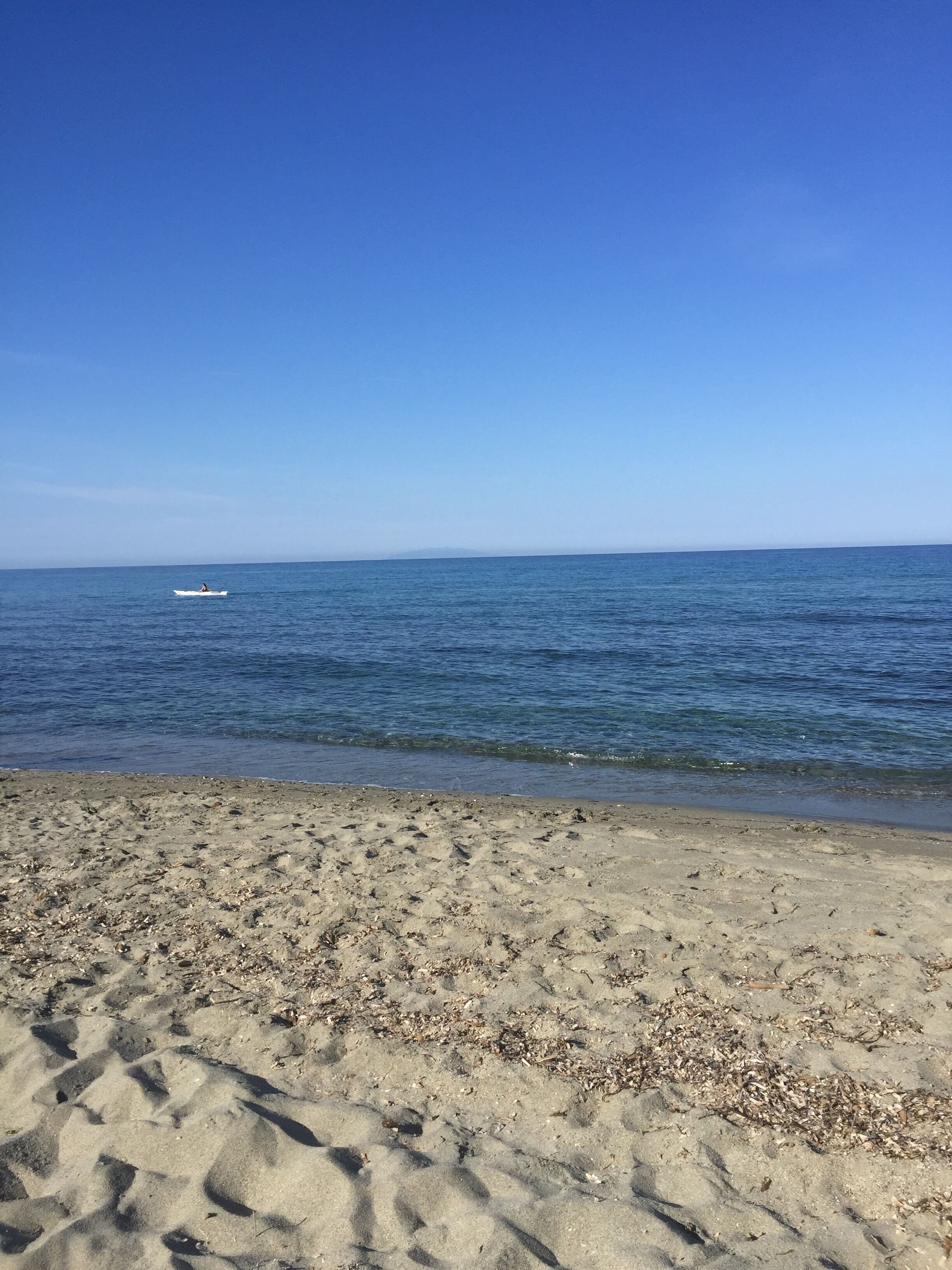 A sandy beach with gentle waves and a clear blue sky.
