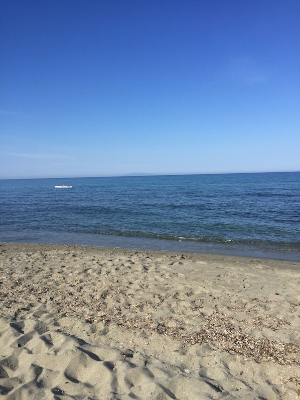 A sandy beach with gentle waves and a clear blue sky.