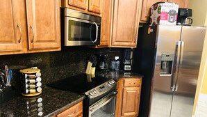 A kitchen with wooden cabinets, a stainless steel refrigerator, a microwave, a stove, and a coffee maker. - Newly renovated modern, spacious & quiet location (Panama City)
