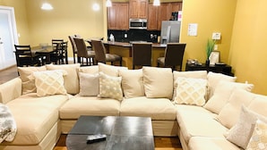 A living room with a beige sectional sofa, a dark wooden coffee table, and a kitchen in the background. - Newly renovated modern, spacious & quiet location (Panama City)