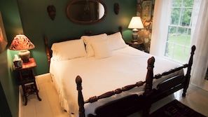 A neatly made bed with white linens in a room with green walls, a wooden headboard, and a window with a view of greenery. - The Notch House (Orleans)