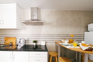 Eine moderne Küche mit Gasherd, Toaster, Kaffeemaschine und gedecktem Frühstückstisch.