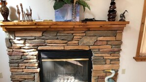 Una chimenea de piedra con repisa de madera, un cuadro enmarcado y una escultura decorativa de un pájaro.