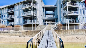 Un edificio de varios pisos con balcones y un muelle que da a una masa de agua.