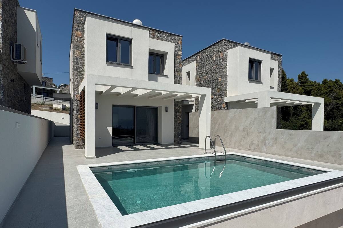 A modern poolside area with a rectangular pool, stone and white exterior walls, and a pergola structure.