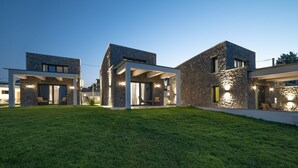 Una casa moderna con fachada de piedra, ventanas amplias y césped cuidado.