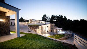 Un moderno complejo residencial con piscina, arquitectura de piedra y hormigón, y césped bien cuidado.