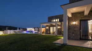Una casa moderna con fachada de piedra, un patio cubierto y una piscina.
