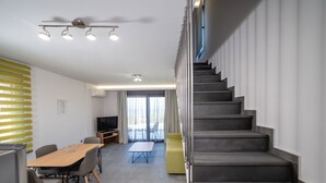 Una sala de estar moderna con una escalera, un comedor y un televisor.