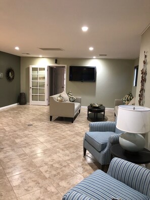 Relax in this open-plan living space with a sofa, armchairs, and a flat-screen TV.