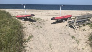 A sandy beach with two red paddleboards and a wooden bench. - Beachfront Home-Fully Furnished.  PRIVATE Beach Rights on L.I. Sound. (Mt Sinai)