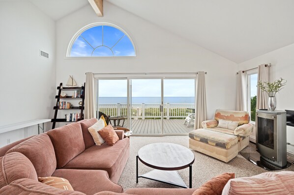 A spacious living room with a large window, a cozy sofa, a small table, and a fireplace.