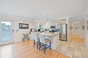 A modern kitchen with a central island, stainless steel appliances, and a dining area with two chairs.
