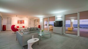 A modern living room with a sofa, red chairs, a glass coffee table, and a TV. - Villa 308 - Coral Estate (Rif. St. Marie)
