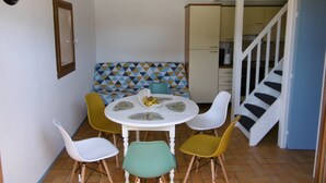 A dining area with a round table, six chairs, and a patterned sofa. - HOUSE WITH HEATED POOL CLOSE TO BEACHES AND NATIONAL FOREST (Saint-Jean-de-Monts, Vendée)