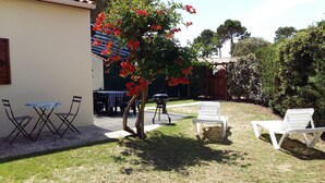 A patio with a table and chairs, a barbecue grill, and a tree with red flowers. - HOUSE WITH HEATED POOL CLOSE TO BEACHES AND NATIONAL FOREST (Saint-Jean-de-Monts, Vendée)